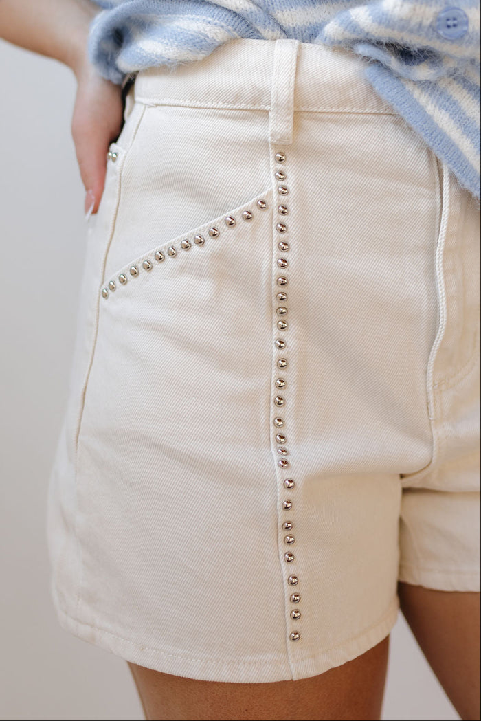 Beige shorts with decorative studs on a neutral background